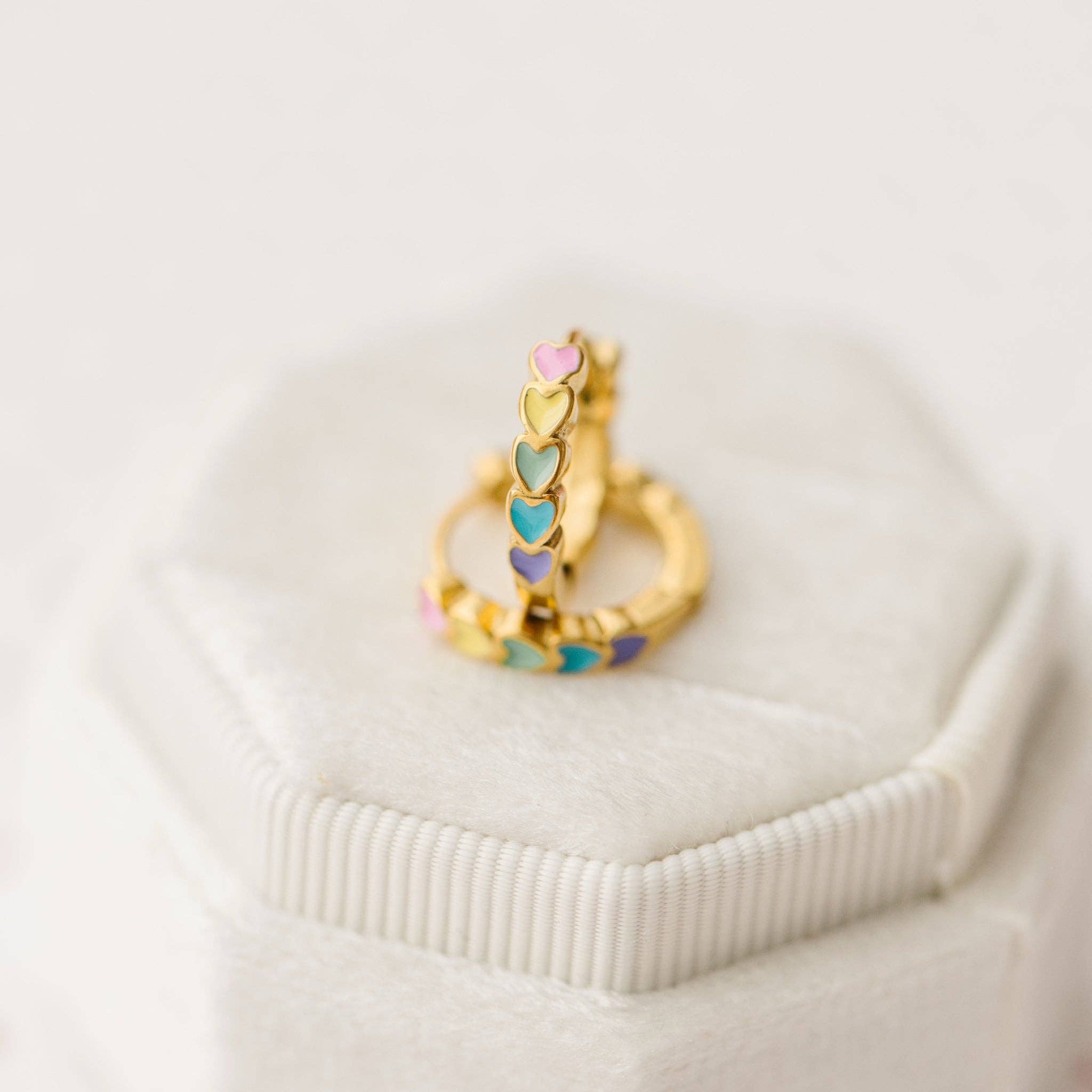 Gold ring with colorful heart-shaped stones on a white surface