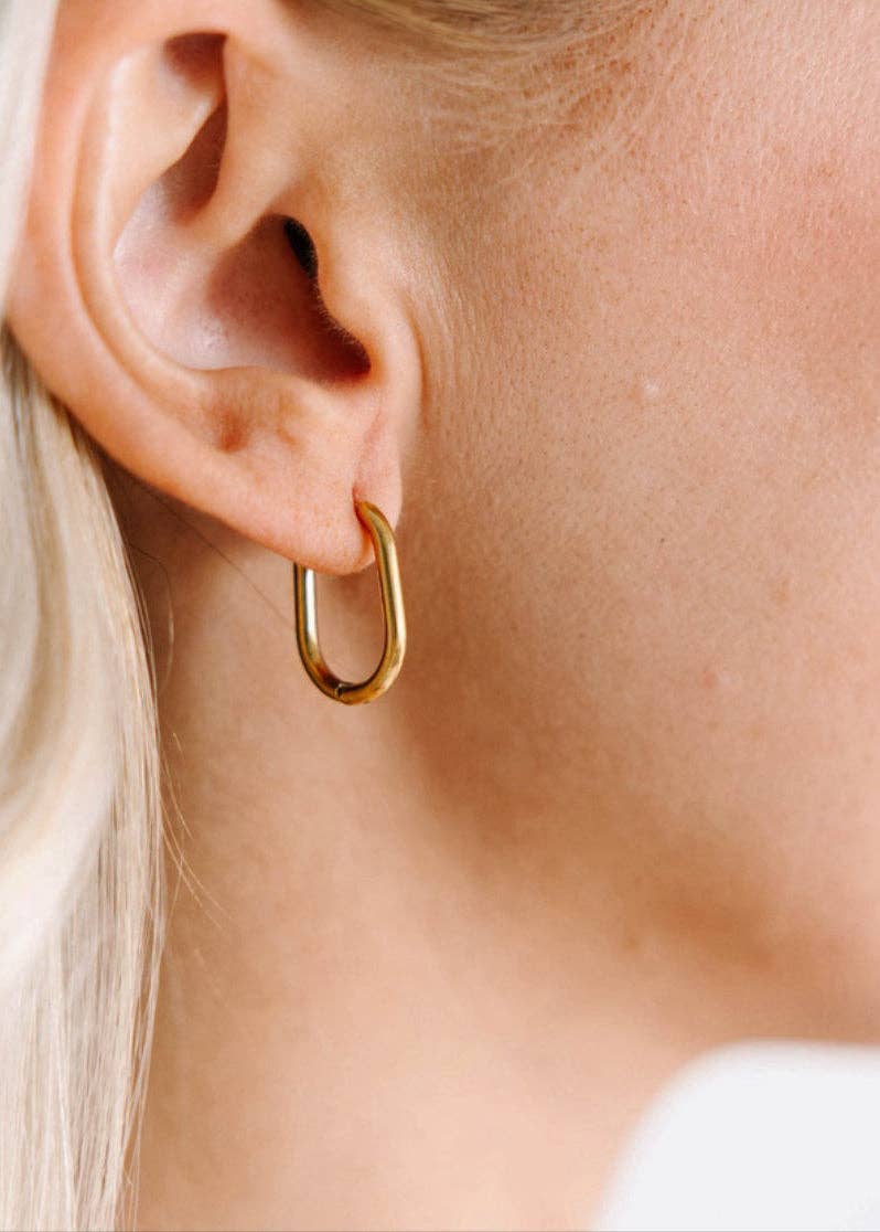 Gold hoop earring worn by a person with blonde hair.