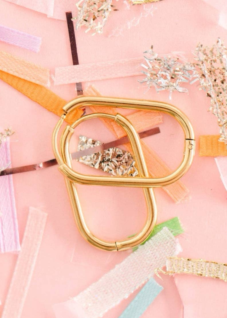 Gold hair accessories on a pink background with decorative ribbons and flowers.
