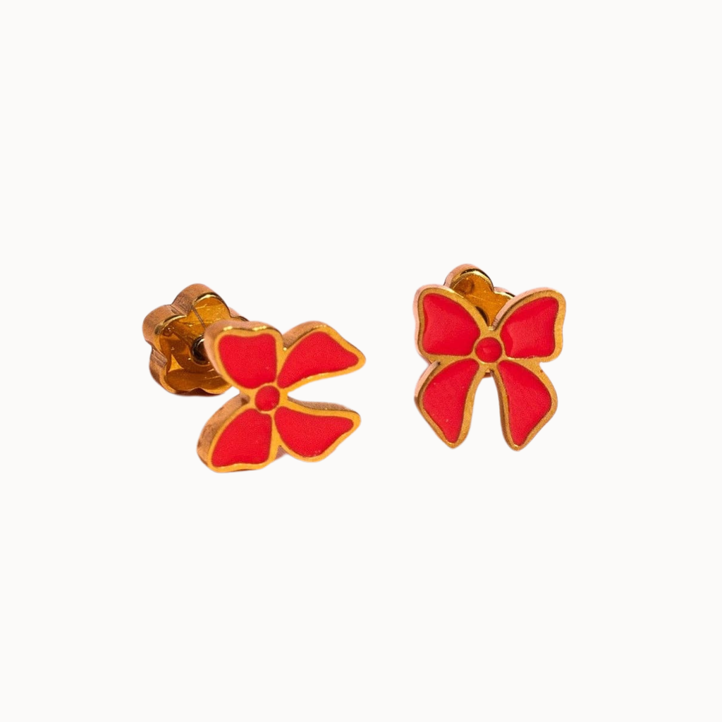 A pair of gold-tone stud earrings shaped like stylized flowers with bright red enamel petals, shown on a plain off-white background.