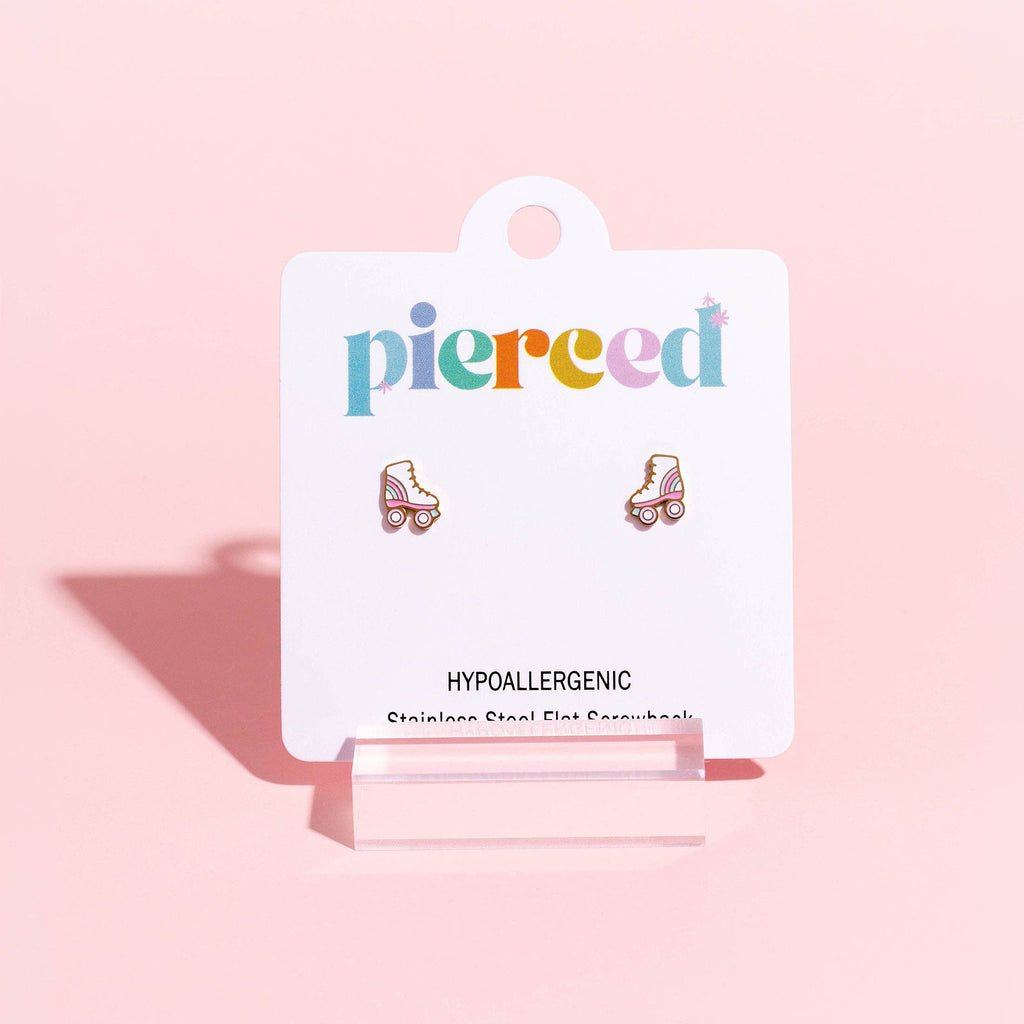 A pair of small roller skate stud earrings displayed on a white card backing that reads 'pierced' and 'HYPALLERGGENIC,' set against a soft pink background.