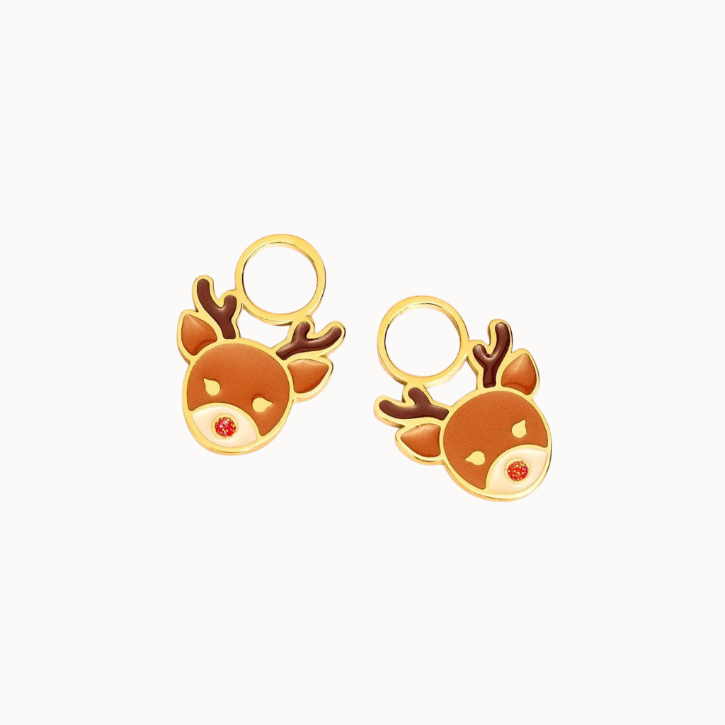 A pair of gold-toned stud earrings shaped like cartoon reindeer heads with brown antlers, a warm orange-brown face, and a small red nose, shown on a plain light background.