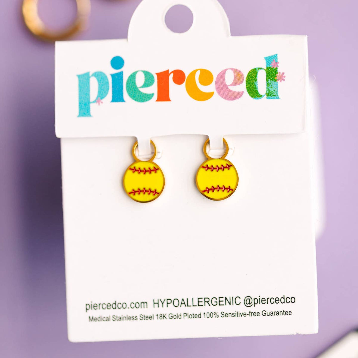 Yellow softball earrings on a 'pierced' branded card with a purple background