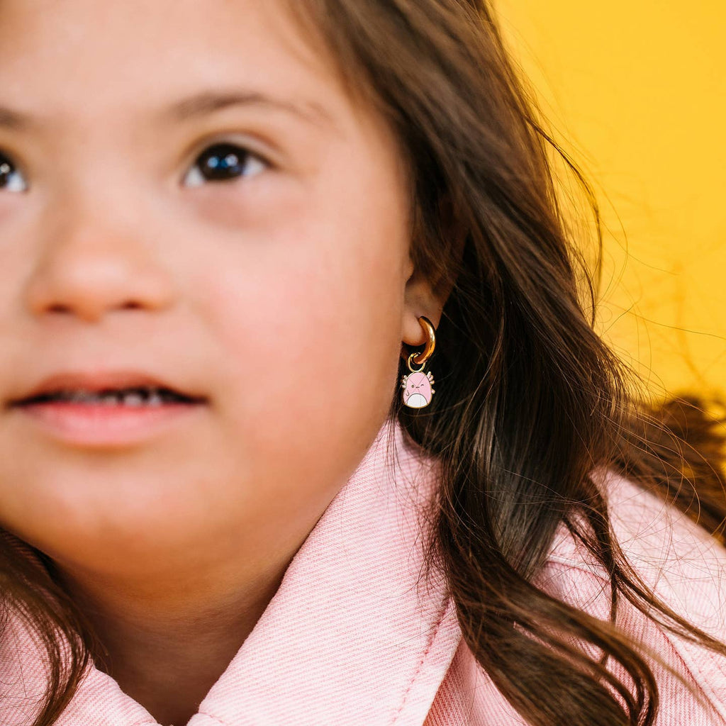 Close-up of a child wearing earrings with a yellow background