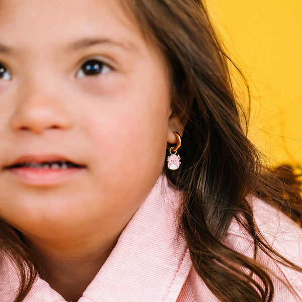 Close-up of a child wearing earrings with a yellow background