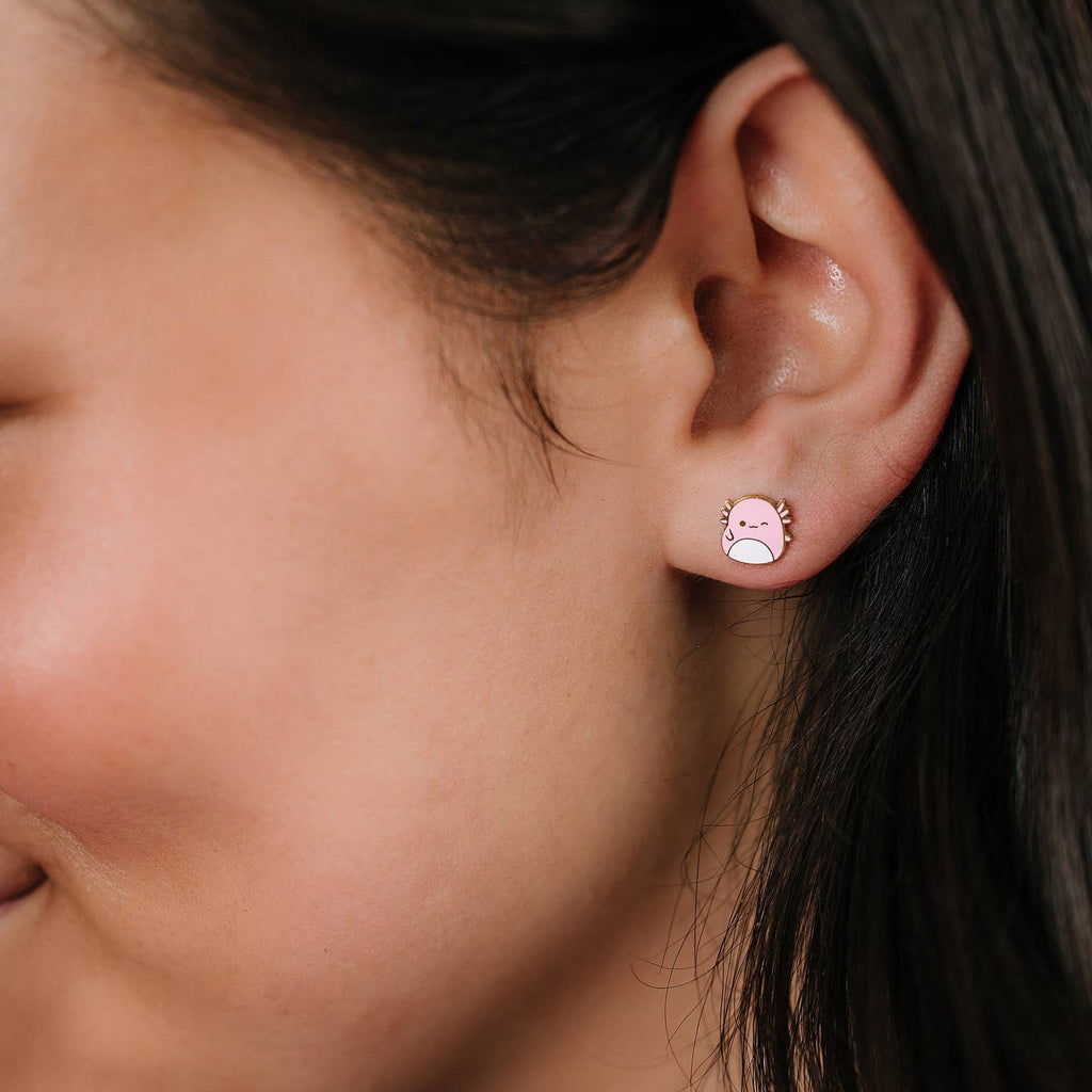 Close-up of an ear wearing a small pink earring with a face design.