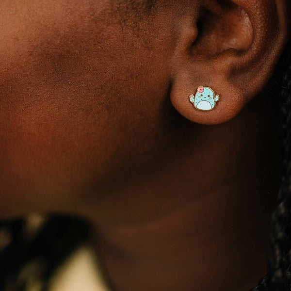 Close-up of an ear wearing a small, round earring with a cartoon character design.