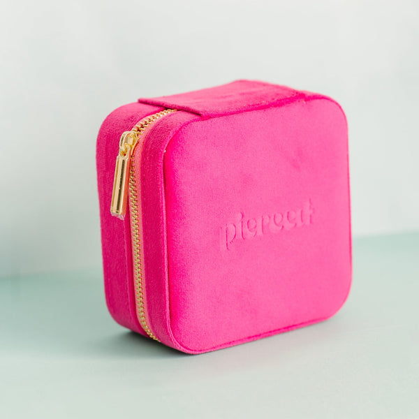 Pink travel case with gold zipper on a light gray background