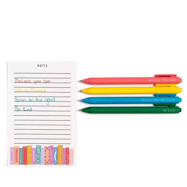 Colorful pens with motivational quotes next to a notepad on a white background