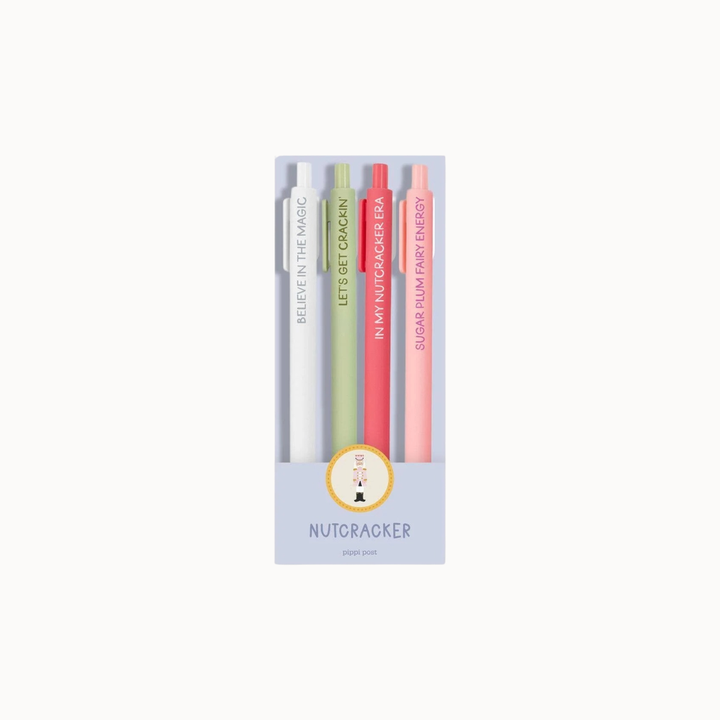 A boxed set of four slim pens in pastel colors: white, light green, coral pink, and peach. The pens are displayed in a clear window box with a lavender base and the brand name Nutcracker printed below.