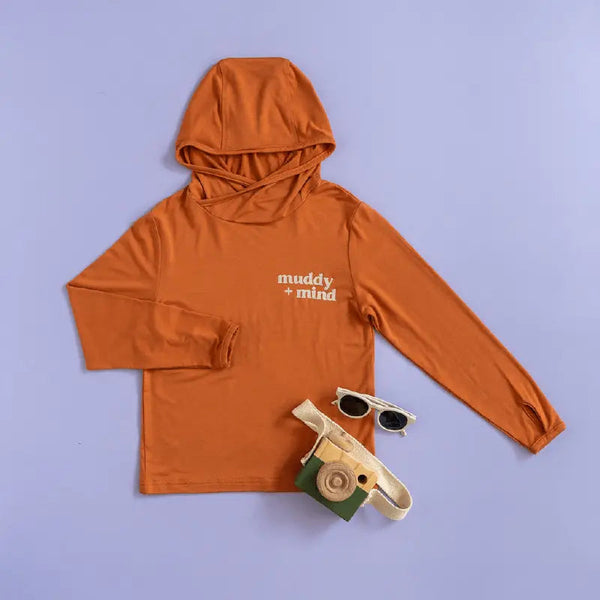 Orange hoodie with 'muddy mind' text, sunglasses, and toy on a purple background