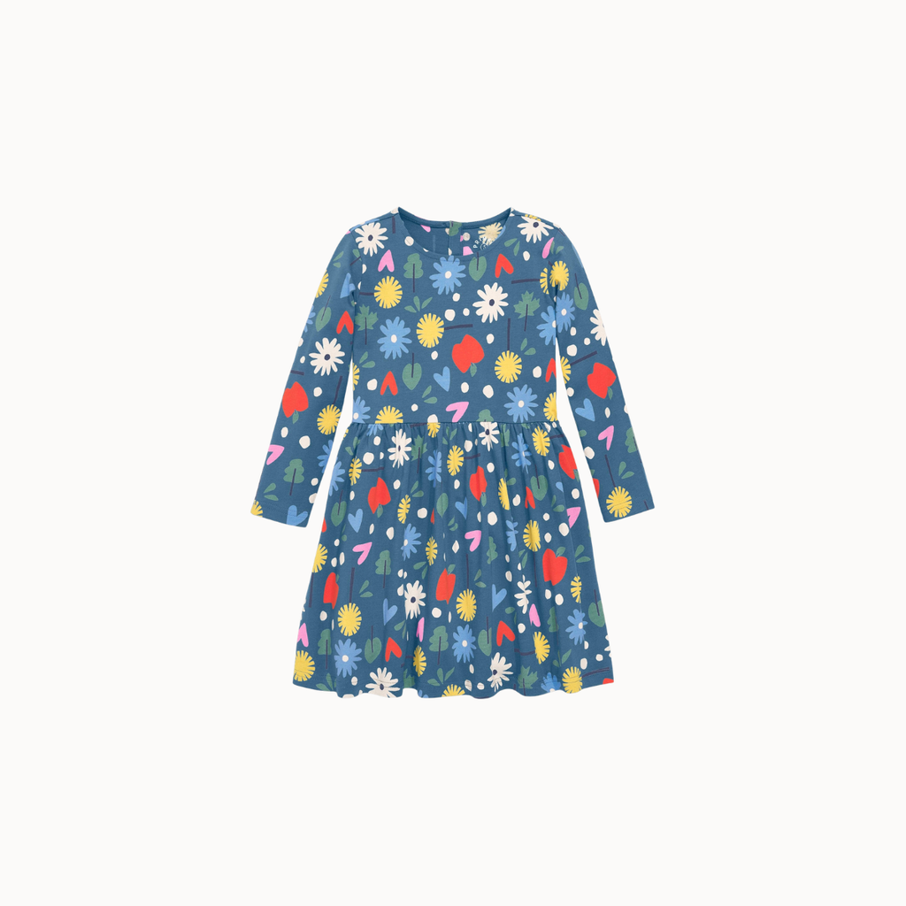 Blue fabric dress with a colorful floral and fruit print, including yellow flowers, green leaves, a red apple, and white dots, finished with a button closure at the neckline on a white background.