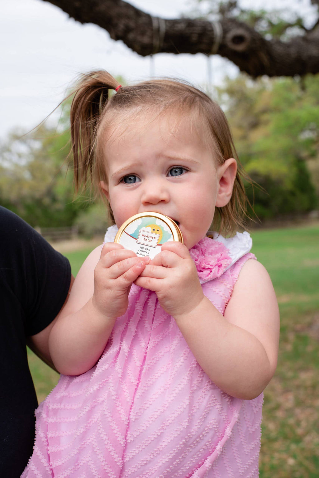 Child holding a product in a park setting