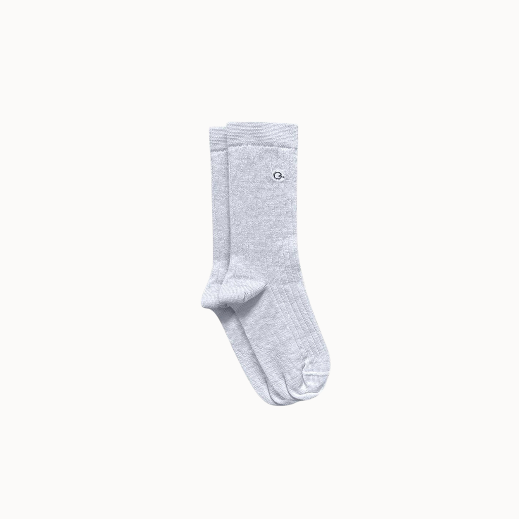 A pair of light gray ribbed socks with shown against a solid light gray background.
