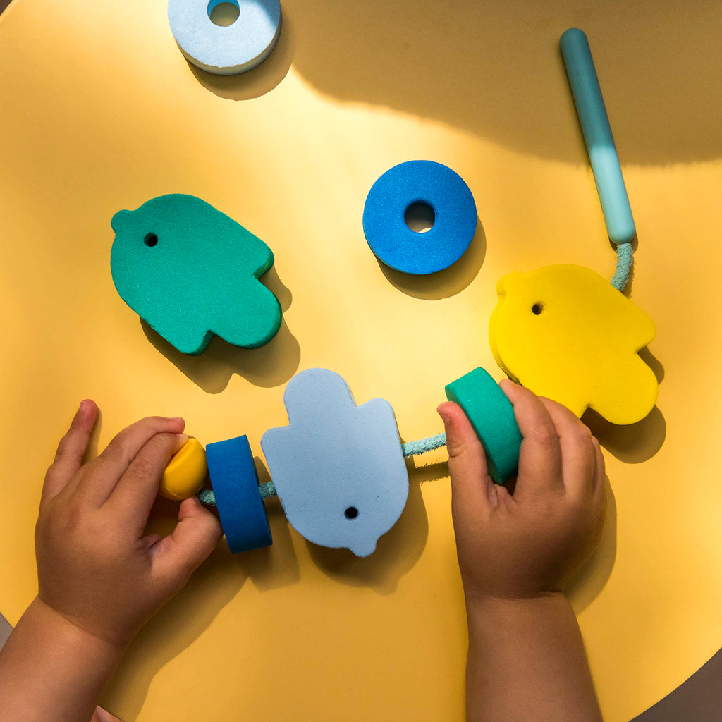 Child's hands playing with colorful wooden toys on a yellow surface