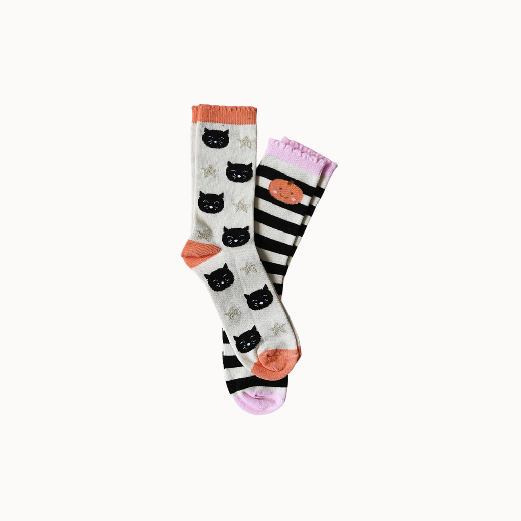 A pair of knee-high socks with a Halloween theme, featuring black cat faces on a white background, black and white stripes with a pumpkin face, and orange and pink accents.