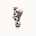 A pair of knee-high socks with a Halloween theme, featuring black cat faces on a white background, black and white stripes with a pumpkin face, and orange and pink accents.