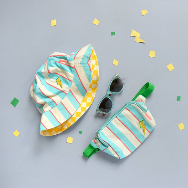 Colorful striped bucket hat and fanny pack with sunglasses on a light gray background