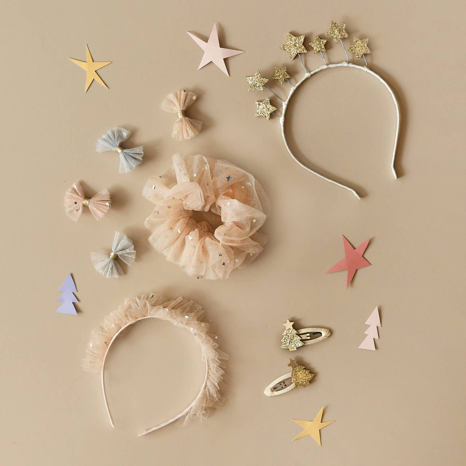 Collection of hair accessories including headbands, scrunchies, and clips on a beige background with decorative stars.