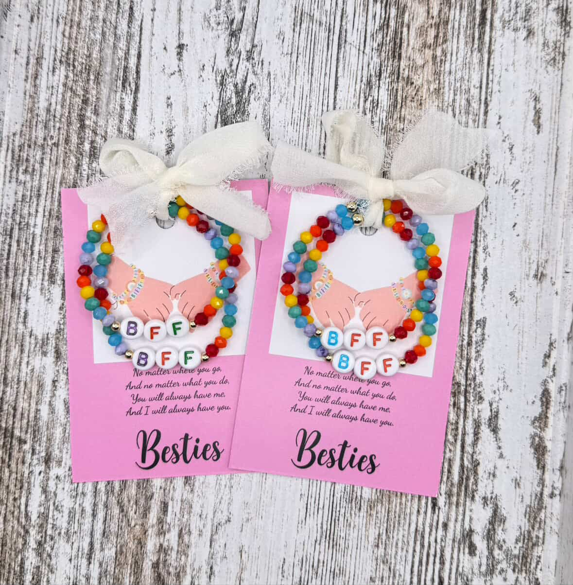 Two colorful beaded bracelets with 'BFF' on pink cards tied with ribbons on a wooden surface.