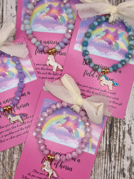 Unicorn-themed bracelets on pink cards with ribbons.