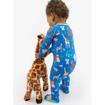 Child wearing a blue pajama with animal print holding a stuffed giraffe toy on a white background