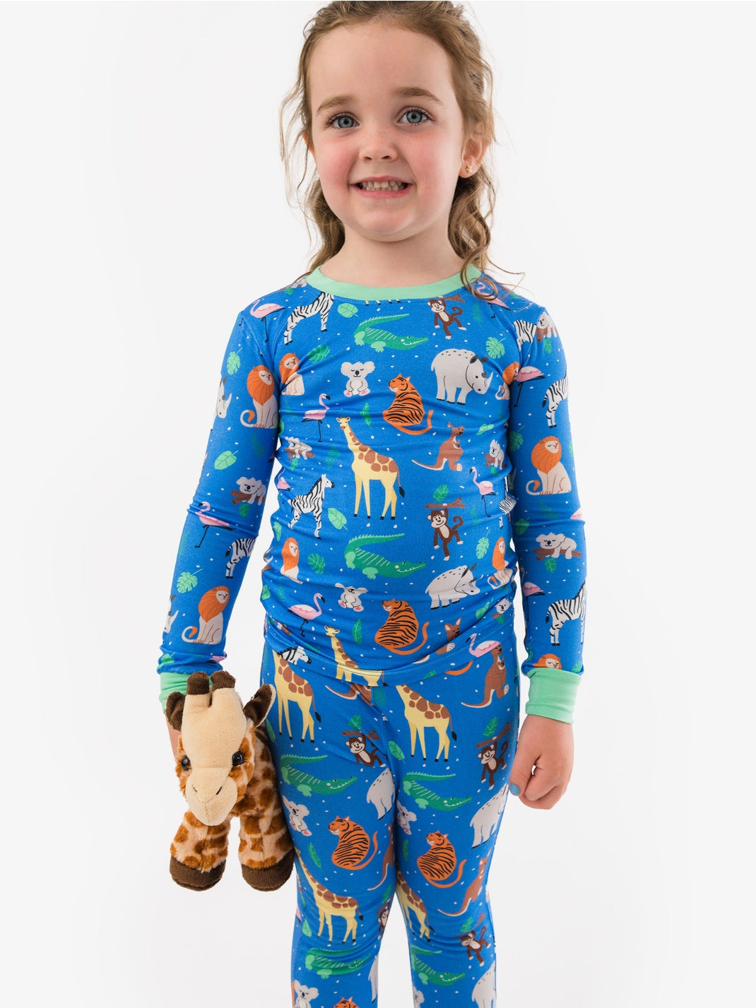 Child wearing a blue pajama set with animal print, holding a plush toy, on a white background