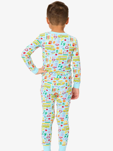 Child wearing a colorful onesie with vehicle pattern on a white background