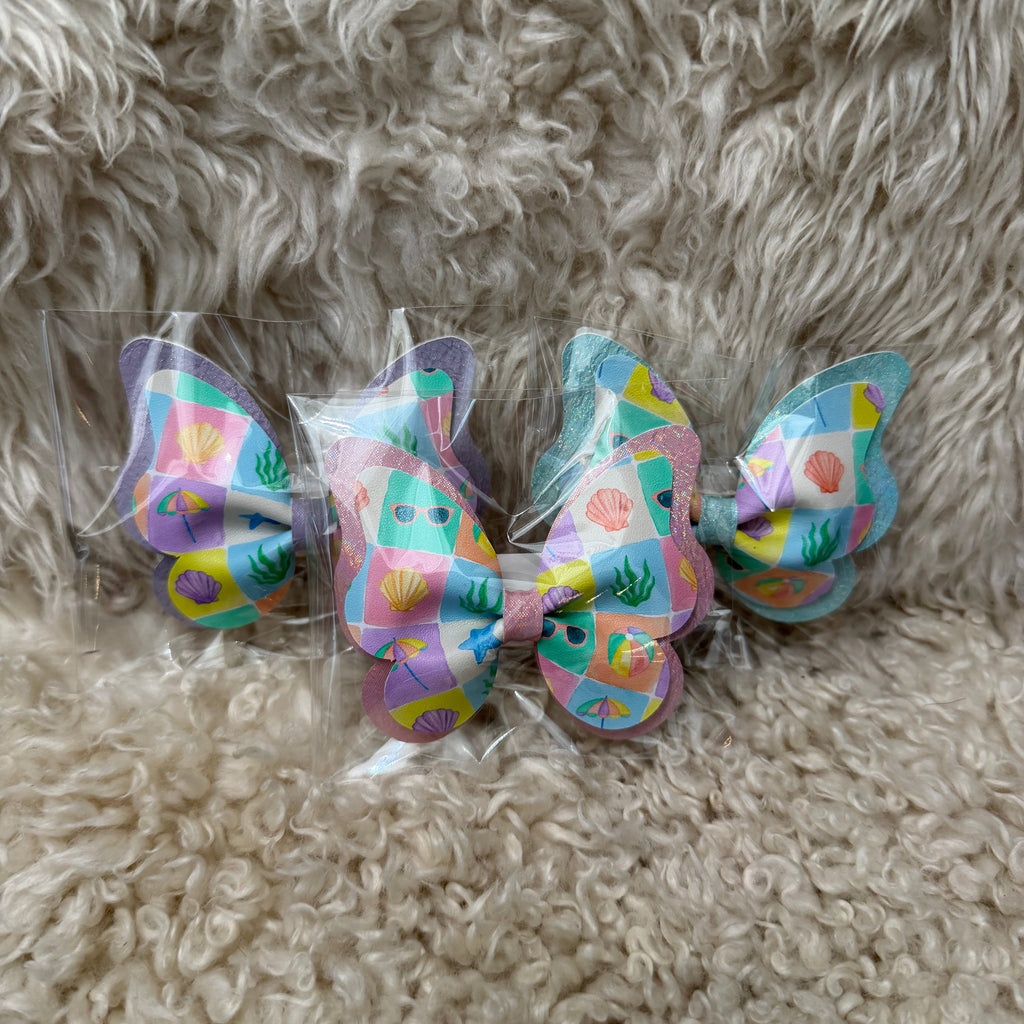 Colorful butterfly-shaped hair clips on a fluffy beige surface