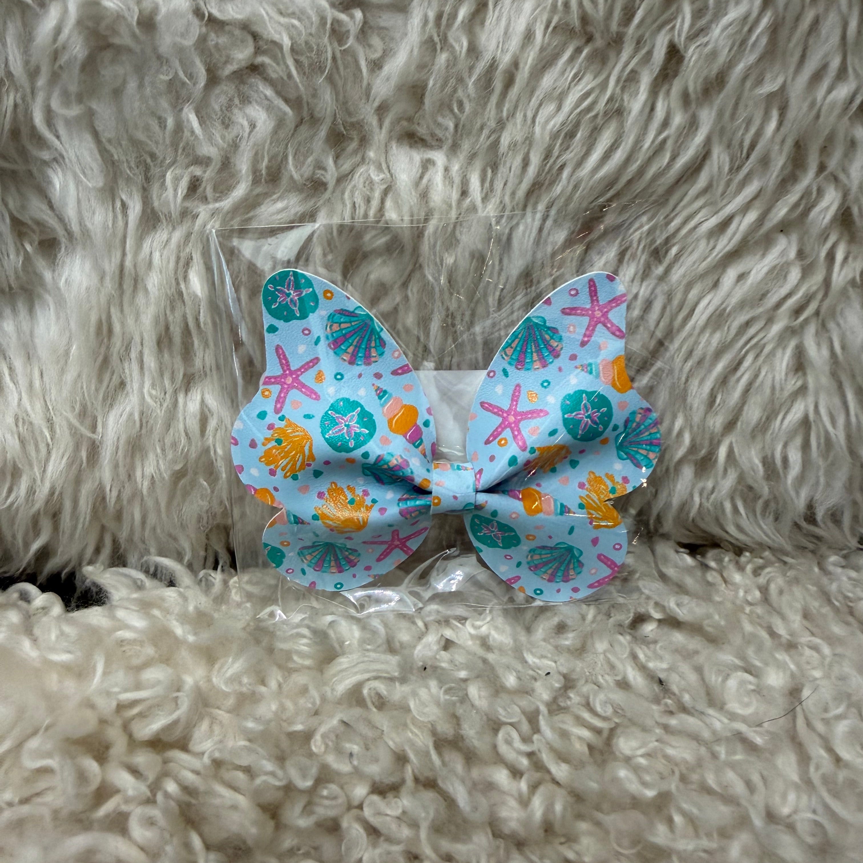 Colorful starfish-themed hair bow on a fluffy beige surface