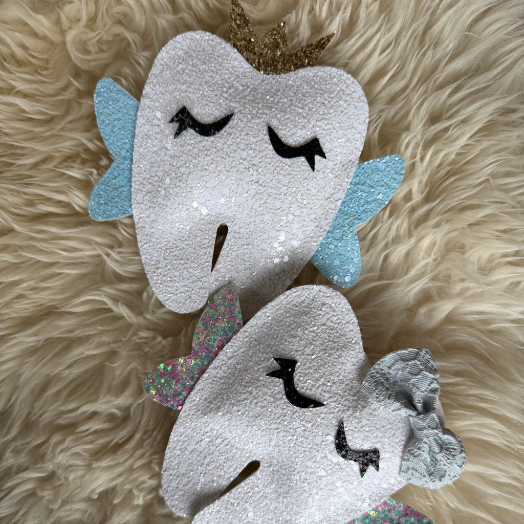 Decorative tooth-shaped pillow with wings and a crown on a fluffy beige surface