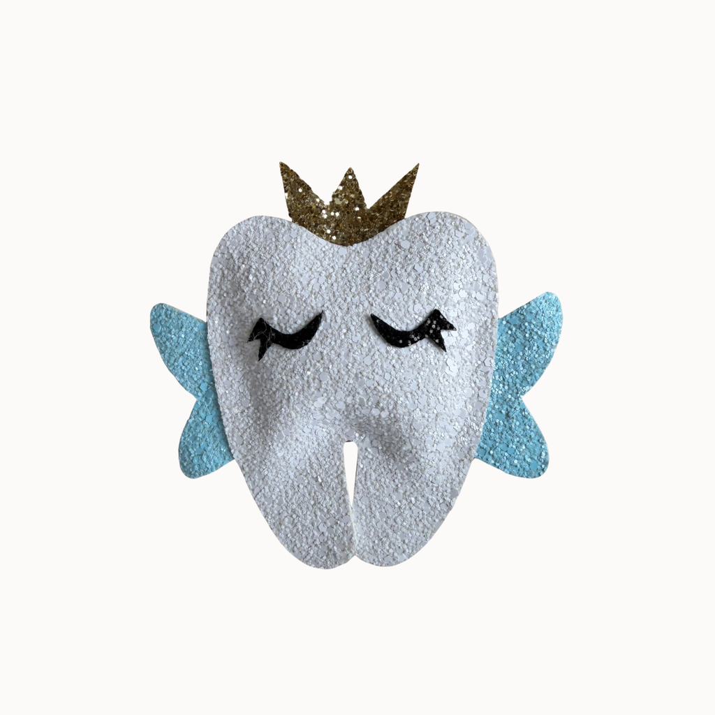 A plush tooth-shaped character accessory with closed black embroidered eyes, light blue wings, and a glittery gold crown, shown on a plain off-white background.