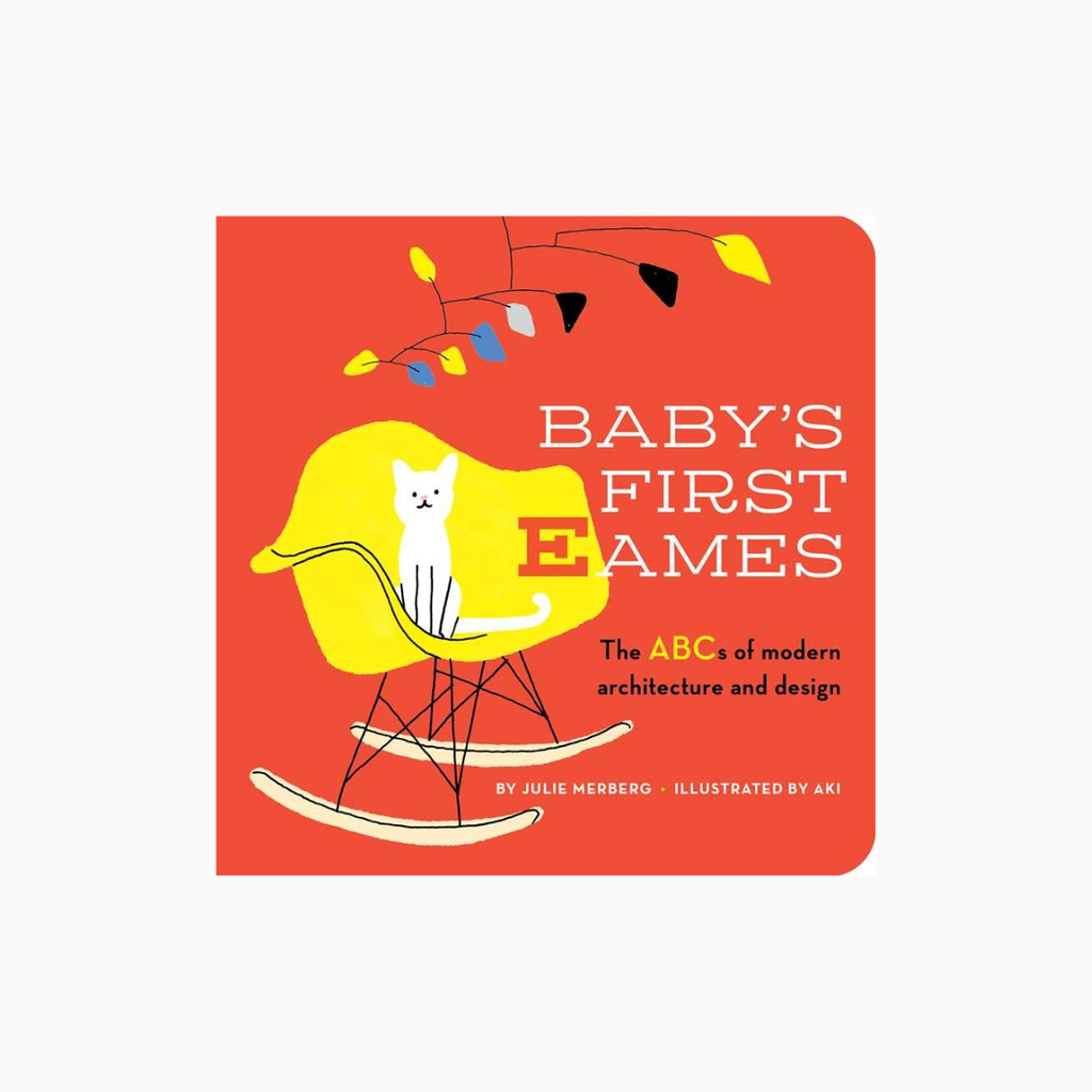 Front cover of the children's book 'Baby's Firstames: The ABCs of modern architecture and design' by Julie Herrberg, illustrated by Aki. The cover features a bold red background with a yellow rocking chair, a white cat, and colorful hanging string lights.