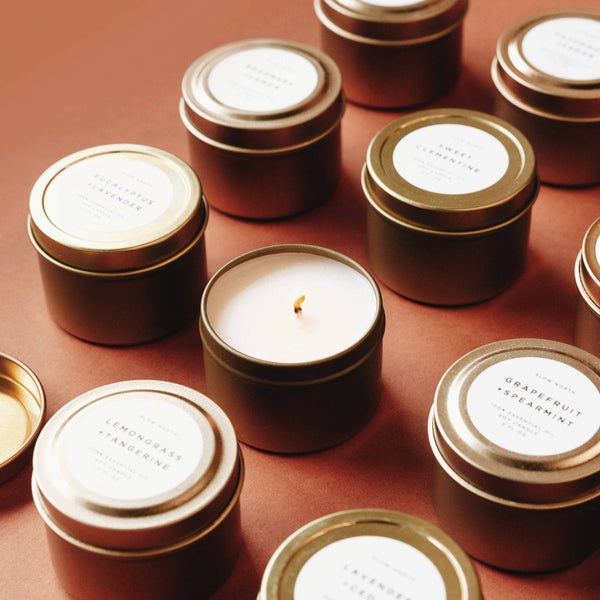 Collection of candles in gold tins with labels on a brown surface
