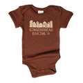 A brown short-sleeve baby bodysuit with a light beige graphic of gingerbread houses and the text 'GINGERBREAD BAKING CO.' printed on the chest, shown against a plain white background.