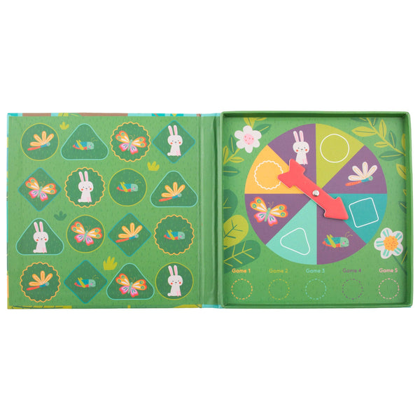 An open children's activity book or game box with green pages, featuring bunny and butterfly illustrations, colored game shapes, and a red spinner pointer.