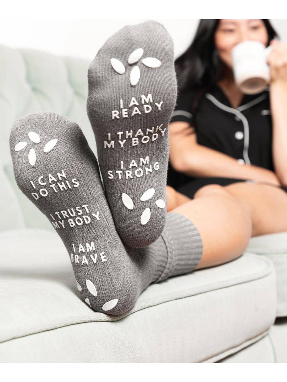 Gray socks with motivational text worn by a person sitting on a couch.