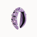 A lavender purple velvet twist headband decorated with small pink and black heart charms, rhinestones, and bat-shaped embellishments, shown against a plain off-white background.