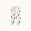 A pair of cream-colored sweatpants featuring a checkerboard pattern and an all-over print of brown gingerbread men, displayed against a solid off-white background.