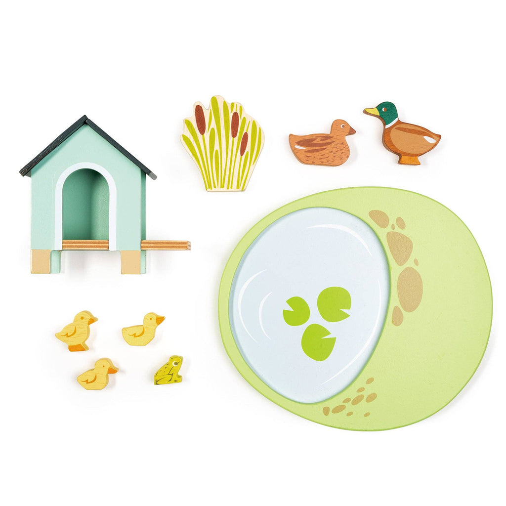 Set of children's play items including a duck, duck house, grass, and pond on a white background