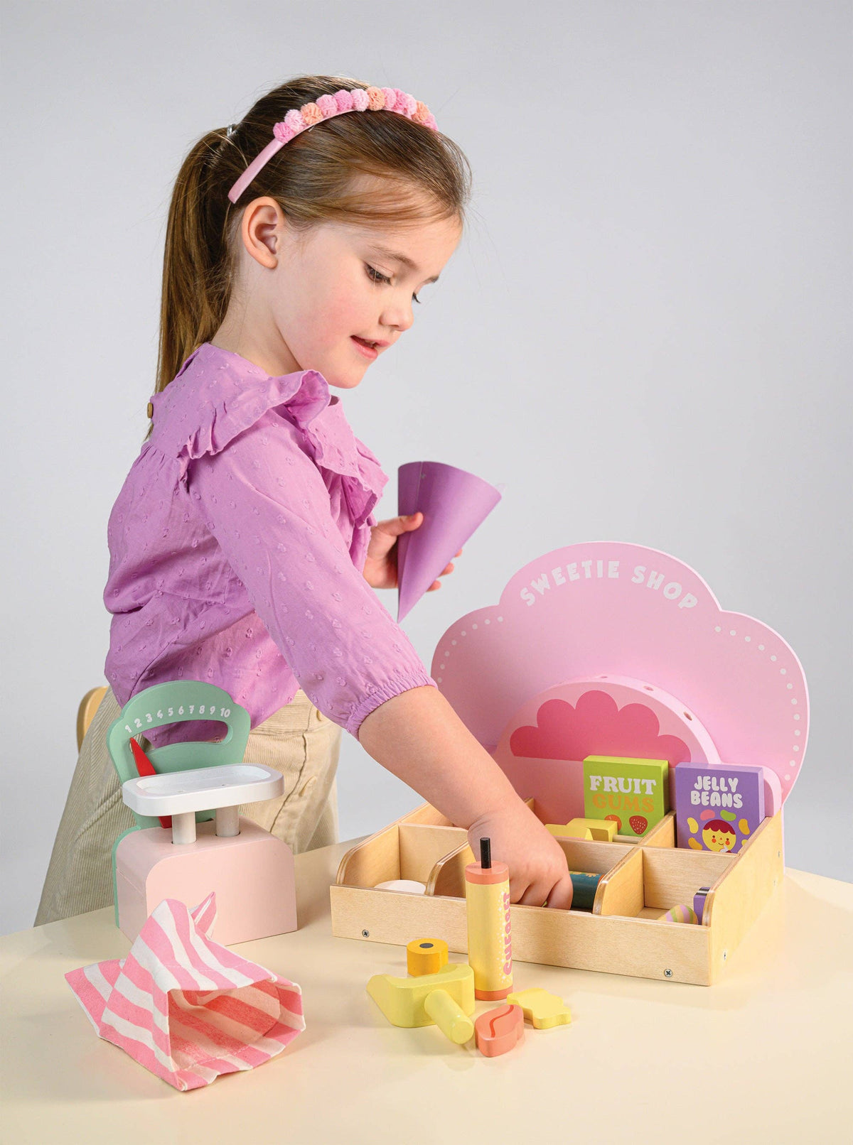 Child playing with a toy set on a table against a plain background