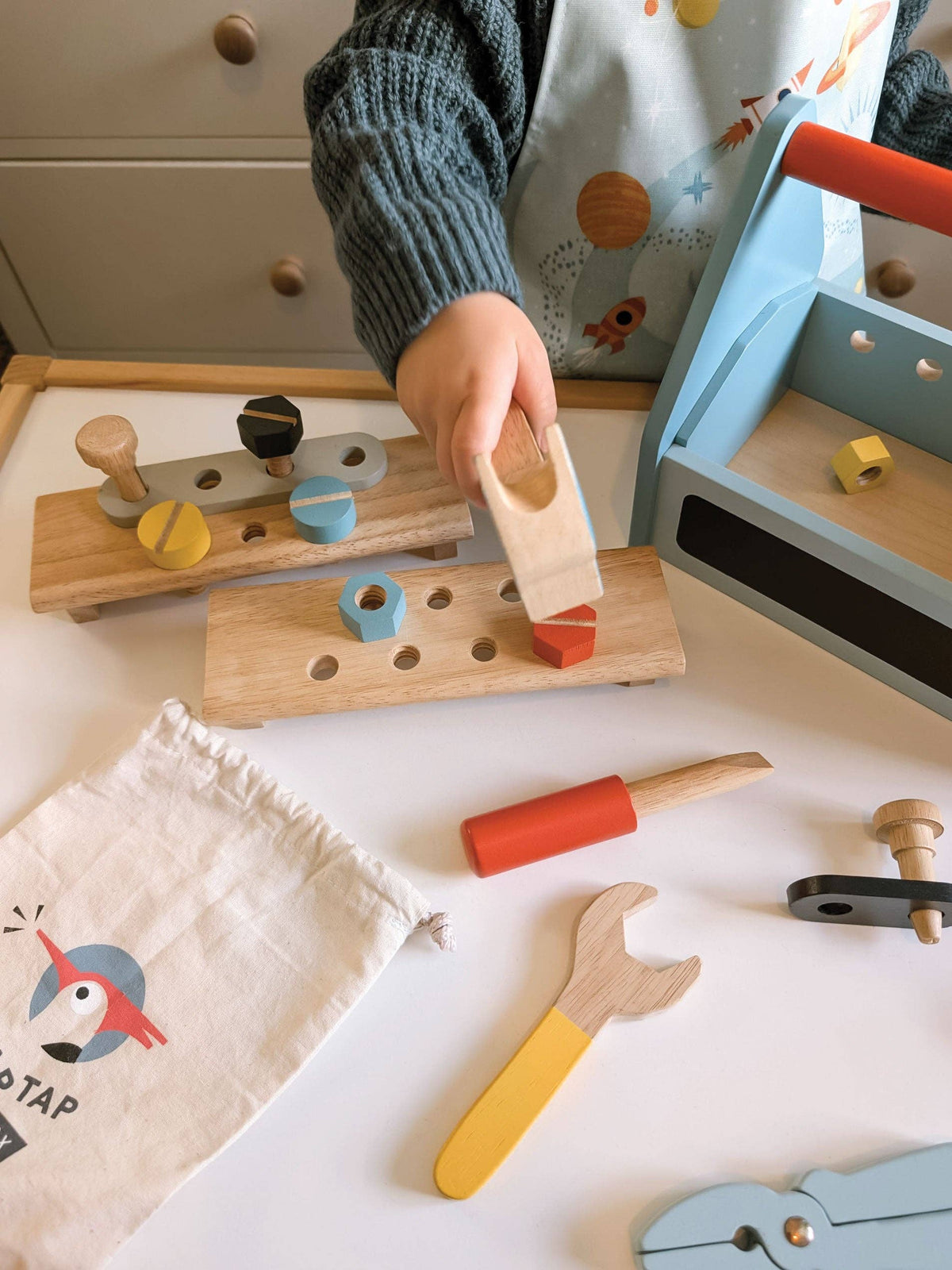 Child playing with wooden tools on a white surface
