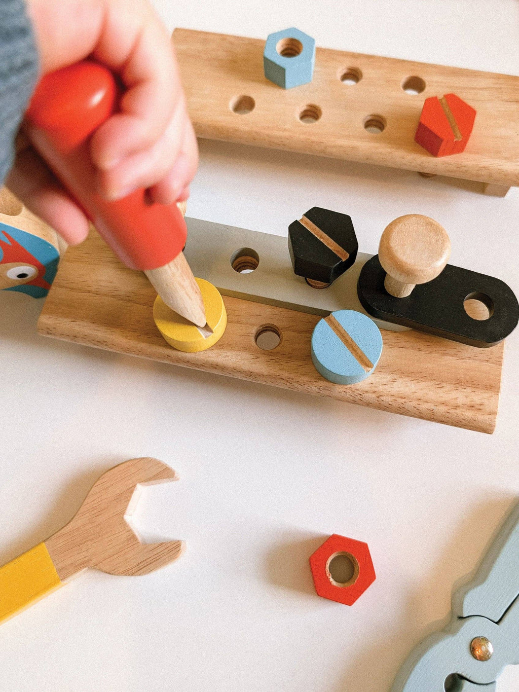 Child playing with a wooden pegboard toy, inserting colorful wooden shapes into holes.