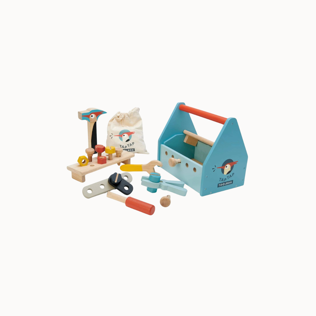 A children's wooden toy toolbox set with a light blue toolbox, workbench, pegs, hammer, wrenches, and a small penguin-themed drawstring bag on a plain white background.