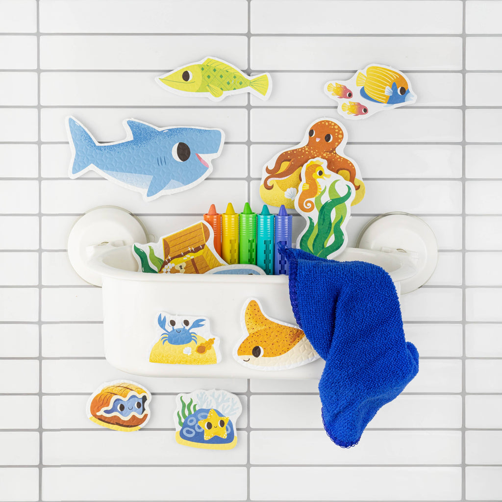 Colorful bath toys including a shark, mermaid, and fish on a tiled bathroom floor.