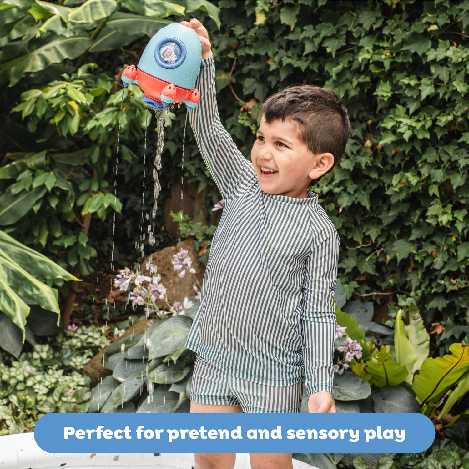 Child playing with a water gun outdoors, surrounded by greenery.