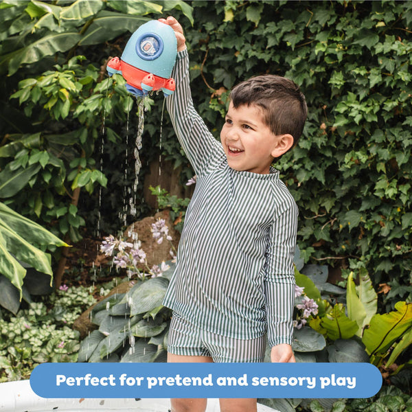 Child playing with a water gun outdoors, surrounded by greenery.