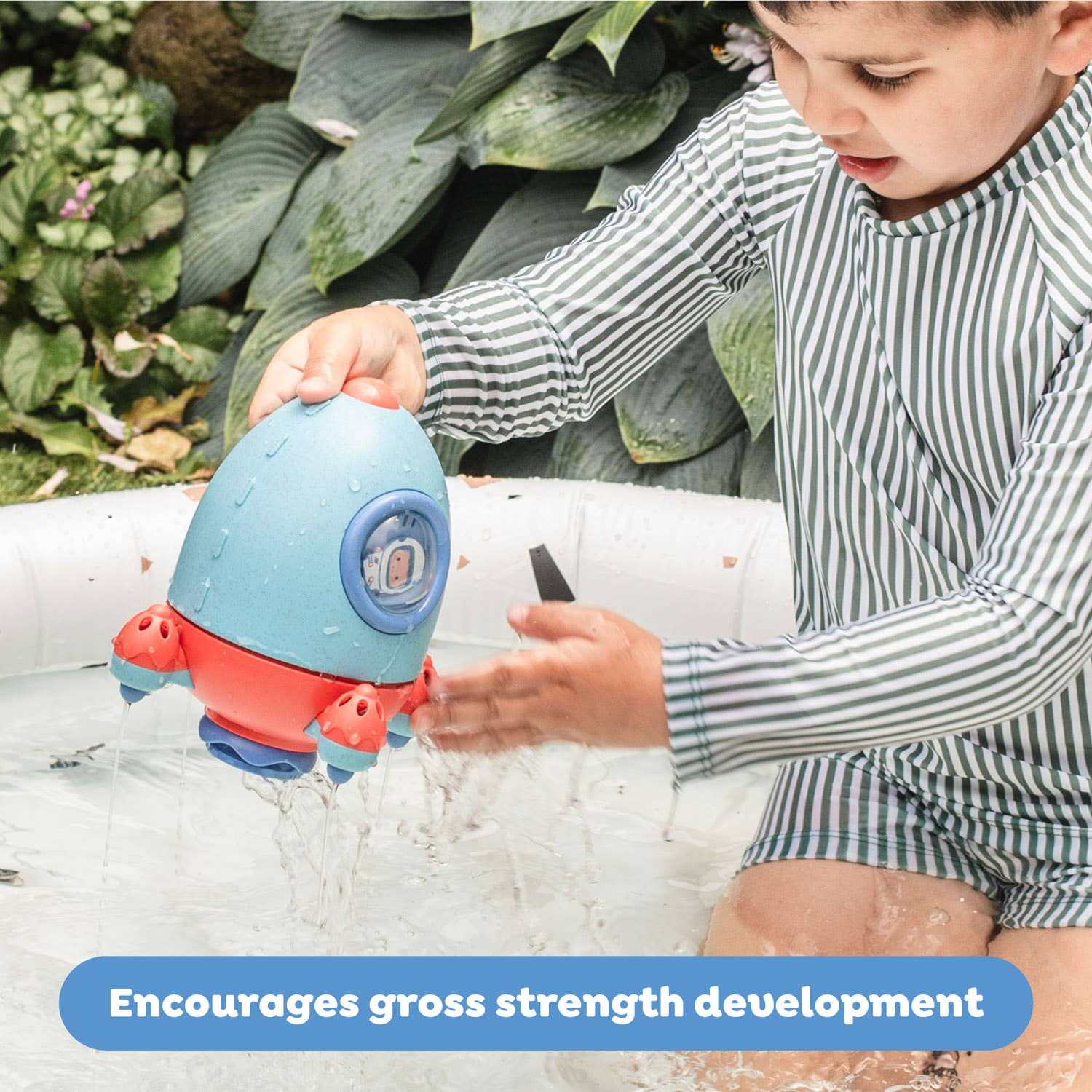 Child playing with a blue and red toy in water, surrounded by greenery.