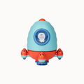 A toy rocket ship in light blue and red with a circular window showing a cartoon astronaut, photographed on a plain light background.