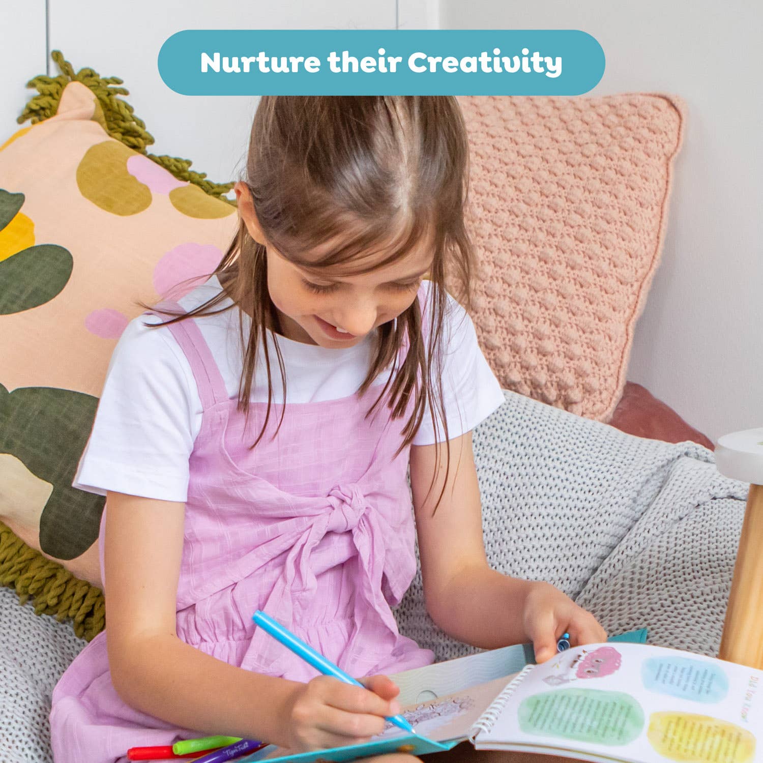 Child drawing in a book with colorful crayons on a cozy couch.